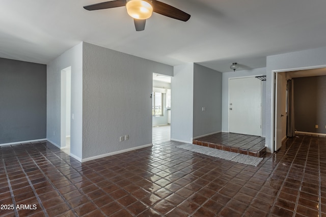 tiled spare room featuring baseboards, a textured wall, and a ceiling fan