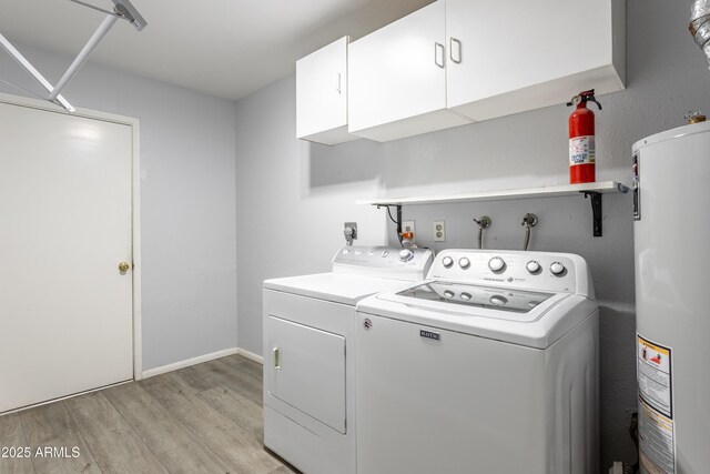laundry area featuring cabinet space, light wood-style floors, water heater, baseboards, and washing machine and dryer
