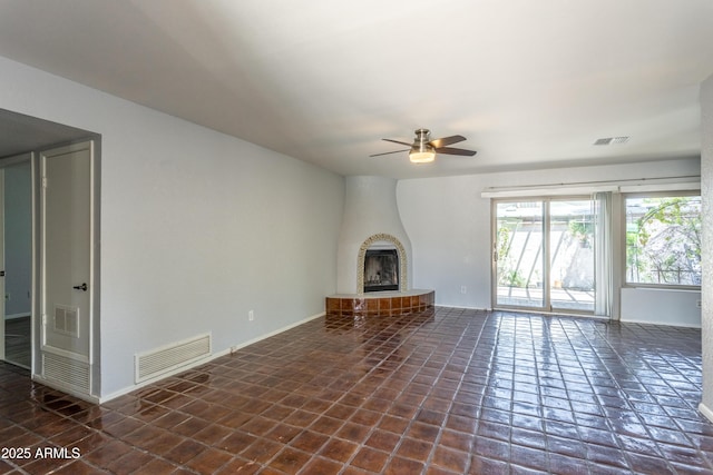 unfurnished living room with visible vents, a ceiling fan, and a fireplace