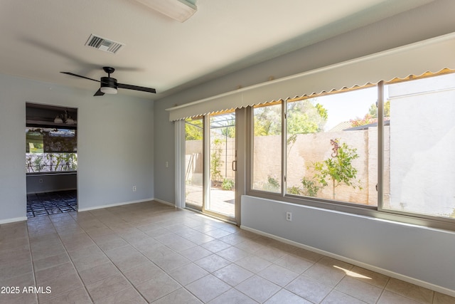 tiled empty room featuring visible vents, baseboards, and ceiling fan