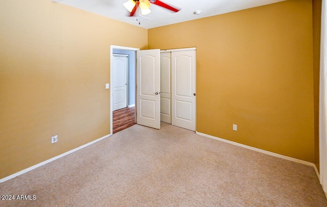 unfurnished bedroom with a closet, light colored carpet, and ceiling fan