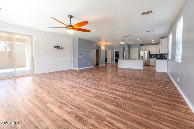 unfurnished living room featuring ceiling fan, hardwood / wood-style flooring, and a wealth of natural light