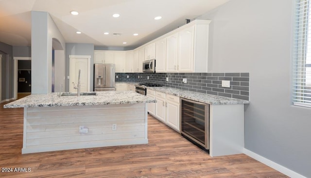 kitchen featuring light wood-type flooring, white cabinets, appliances with stainless steel finishes, and wine cooler