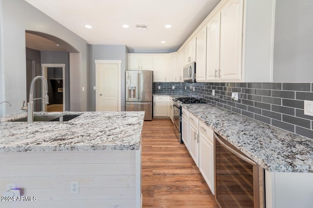 kitchen featuring light hardwood / wood-style floors, wine cooler, sink, stainless steel appliances, and white cabinetry