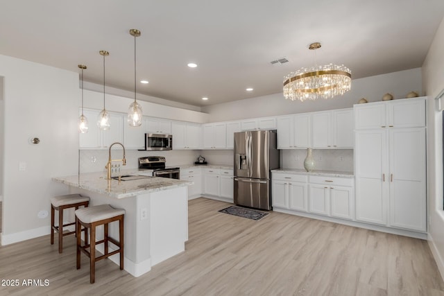 742 W Vineyard Plains Dr, San Tan Valley, AZ 85143 - kitchen with stainless steel appliances, a peninsula, light wood-style flooring, white cabinets, and a chandelier