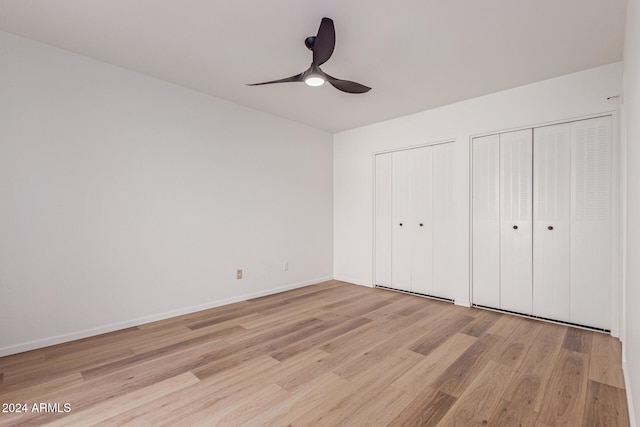 unfurnished bedroom featuring multiple closets, ceiling fan, and light hardwood / wood-style flooring