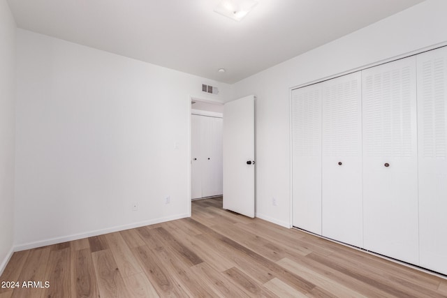 unfurnished bedroom featuring light wood-type flooring and a closet