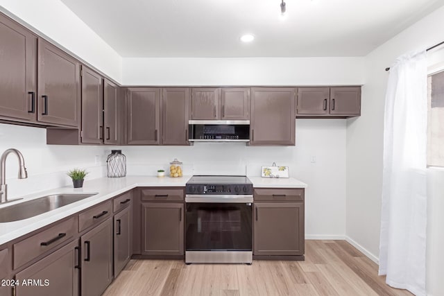 kitchen with sink, stainless steel range, light hardwood / wood-style flooring, dark brown cabinets, and exhaust hood