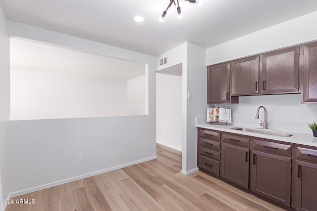 kitchen with dark brown cabinetry, light hardwood / wood-style floors, and sink