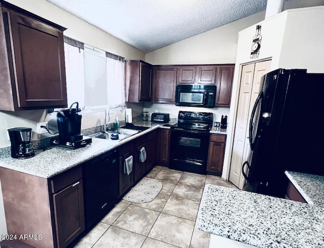 kitchen with vaulted ceiling, light stone counters, a textured ceiling, black appliances, and sink