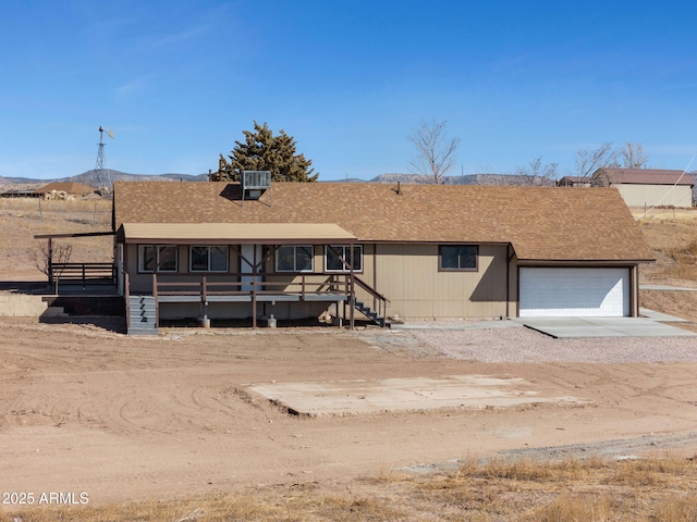 view of front of house with a garage, driveway, and a shingled roof