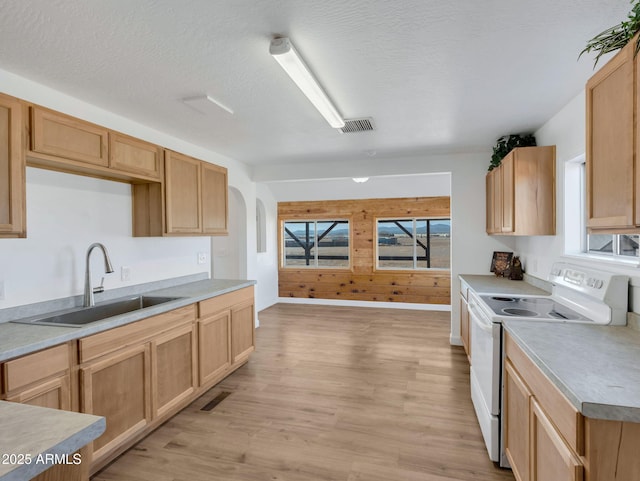 kitchen featuring arched walkways, white electric range oven, visible vents, light wood-style flooring, and a sink