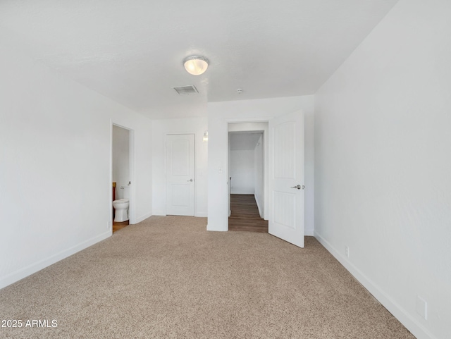 unfurnished bedroom with carpet floors, ensuite bath, baseboards, and visible vents