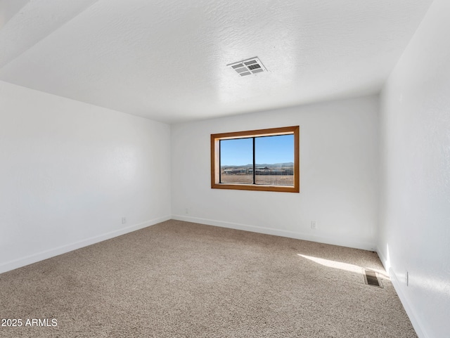 carpeted spare room featuring a textured ceiling, visible vents, and baseboards