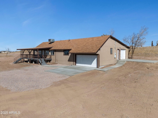 back of property with a garage and a shingled roof