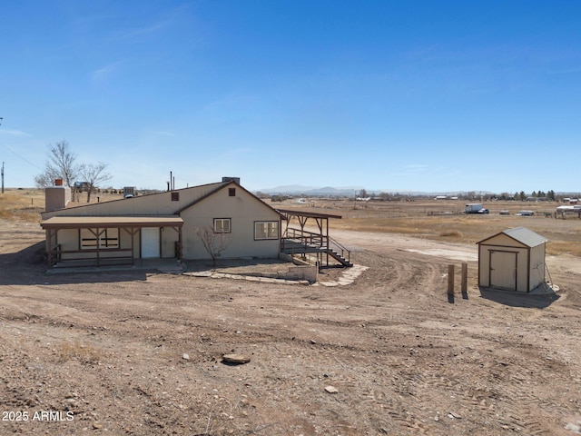 exterior space with a storage shed, a rural view, and an outdoor structure