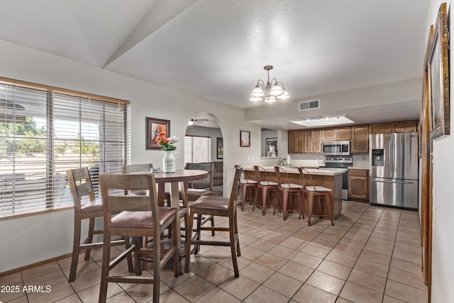 dining space with lofted ceiling, a notable chandelier, and light tile patterned flooring