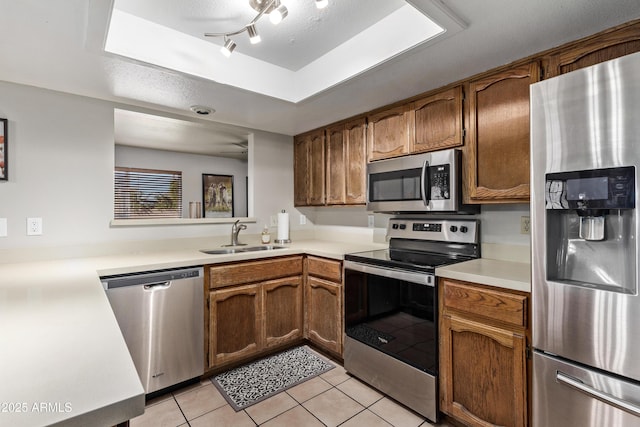 kitchen featuring appliances with stainless steel finishes, rail lighting, a textured ceiling, sink, and light tile patterned floors