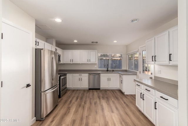 kitchen featuring stainless steel appliances, white cabinetry, sink, and light hardwood / wood-style flooring