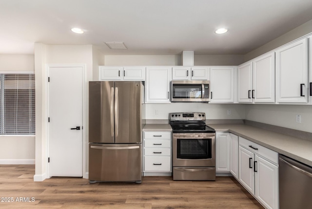 kitchen featuring white cabinets, light hardwood / wood-style flooring, and appliances with stainless steel finishes