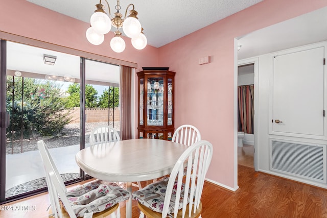 dining room featuring a notable chandelier, light hardwood / wood-style floors, and a textured ceiling