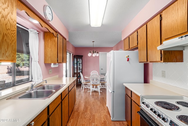 kitchen featuring decorative backsplash, sink, hanging light fixtures, a chandelier, and light hardwood / wood-style flooring