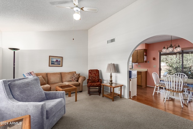 living room with ceiling fan with notable chandelier, hardwood / wood-style flooring, and a textured ceiling