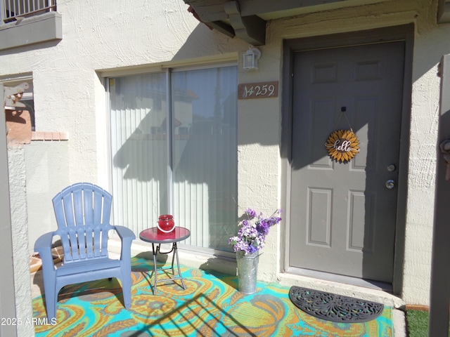 view of exterior entry with stucco siding and a porch