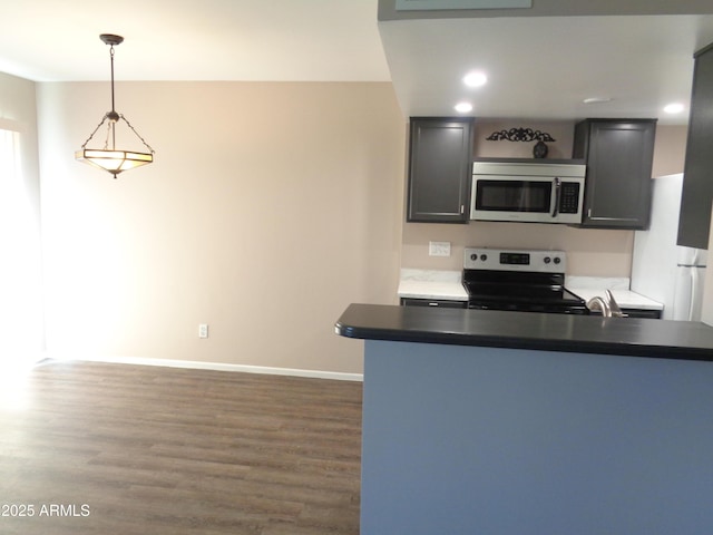 kitchen with decorative light fixtures, stainless steel appliances, baseboards, and wood finished floors