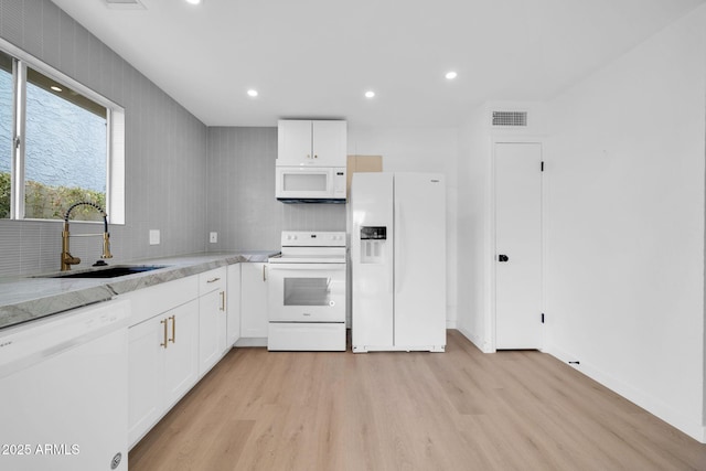 kitchen featuring visible vents, light wood-style floors, white appliances, white cabinetry, and a sink