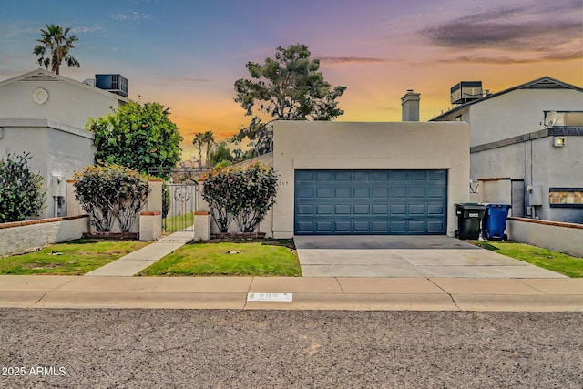 view of front of home featuring stucco siding, a gate, fence, concrete driveway, and an attached garage