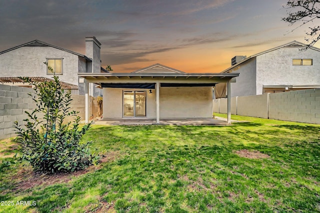 rear view of property with a patio area, stucco siding, a lawn, and a fenced backyard