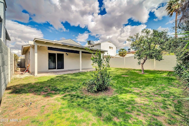 rear view of house with stucco siding, a patio, a lawn, and a fenced backyard