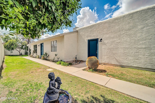 view of front of house with stucco siding, a front lawn, and fence