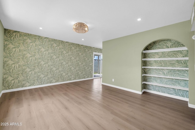 spare room featuring wallpapered walls, recessed lighting, wood finished floors, and baseboards