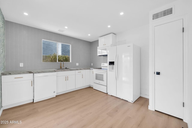 kitchen featuring white appliances, visible vents, light wood finished floors, a sink, and white cabinets