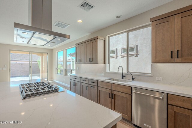 kitchen with decorative backsplash, sink, light stone counters, and appliances with stainless steel finishes