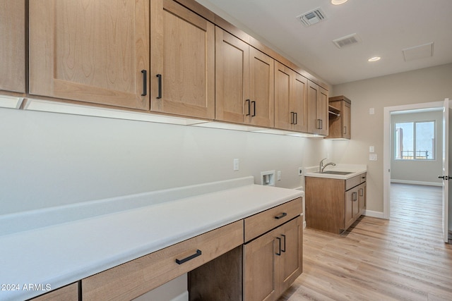 washroom featuring light hardwood / wood-style floors, cabinets, sink, and hookup for a washing machine