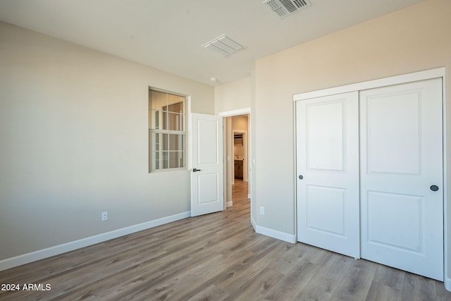 unfurnished bedroom with light wood-type flooring and a closet