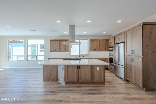 kitchen with a kitchen island, light wood-type flooring, stainless steel appliances, and island range hood