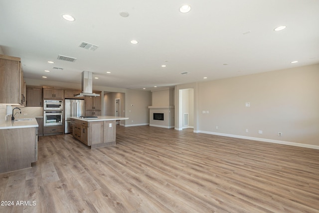 kitchen featuring a center island, ventilation hood, light hardwood / wood-style floors, and sink