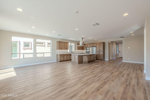 kitchen with island range hood, a kitchen island, light wood-type flooring, and sink