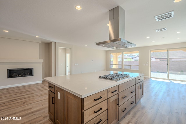 kitchen featuring stainless steel gas cooktop, light hardwood / wood-style flooring, a center island, and ventilation hood