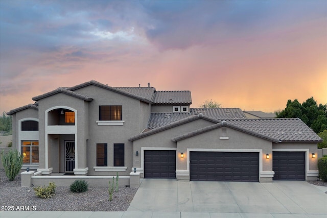 view of front of property with a tiled roof, stucco siding, an attached garage, and concrete driveway