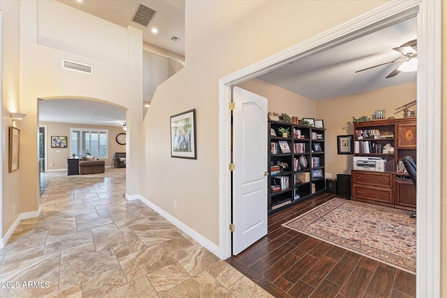 hallway featuring visible vents, arched walkways, baseboards, and wood finished floors