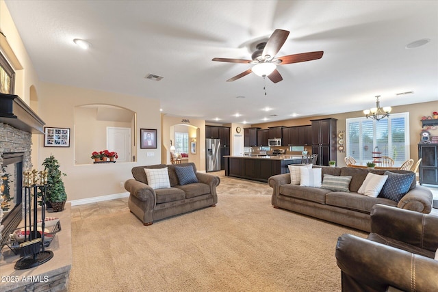 living room with baseboards, visible vents, a fireplace, arched walkways, and ceiling fan with notable chandelier