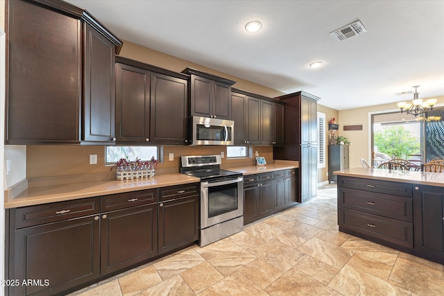 kitchen with visible vents, an inviting chandelier, appliances with stainless steel finishes, light countertops, and dark brown cabinets