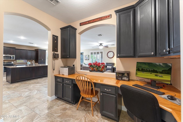 home office with visible vents, a sink, built in desk, baseboards, and ceiling fan