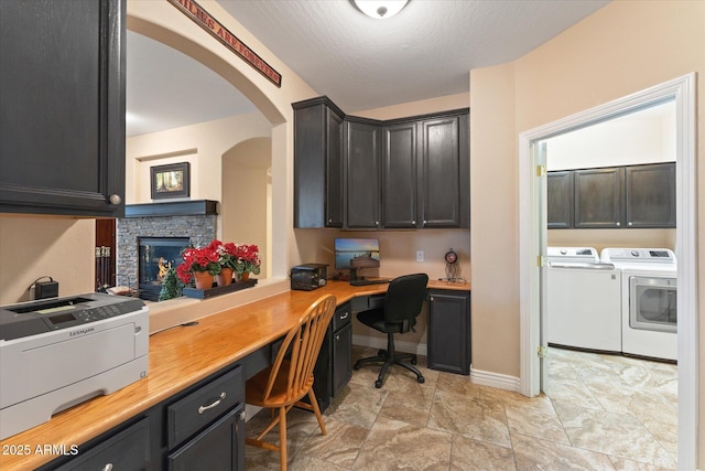 office space with baseboards, a textured ceiling, washing machine and dryer, and built in desk