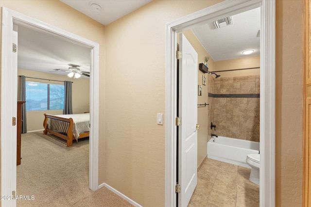 full bath with visible vents, toilet, a ceiling fan, washtub / shower combination, and baseboards